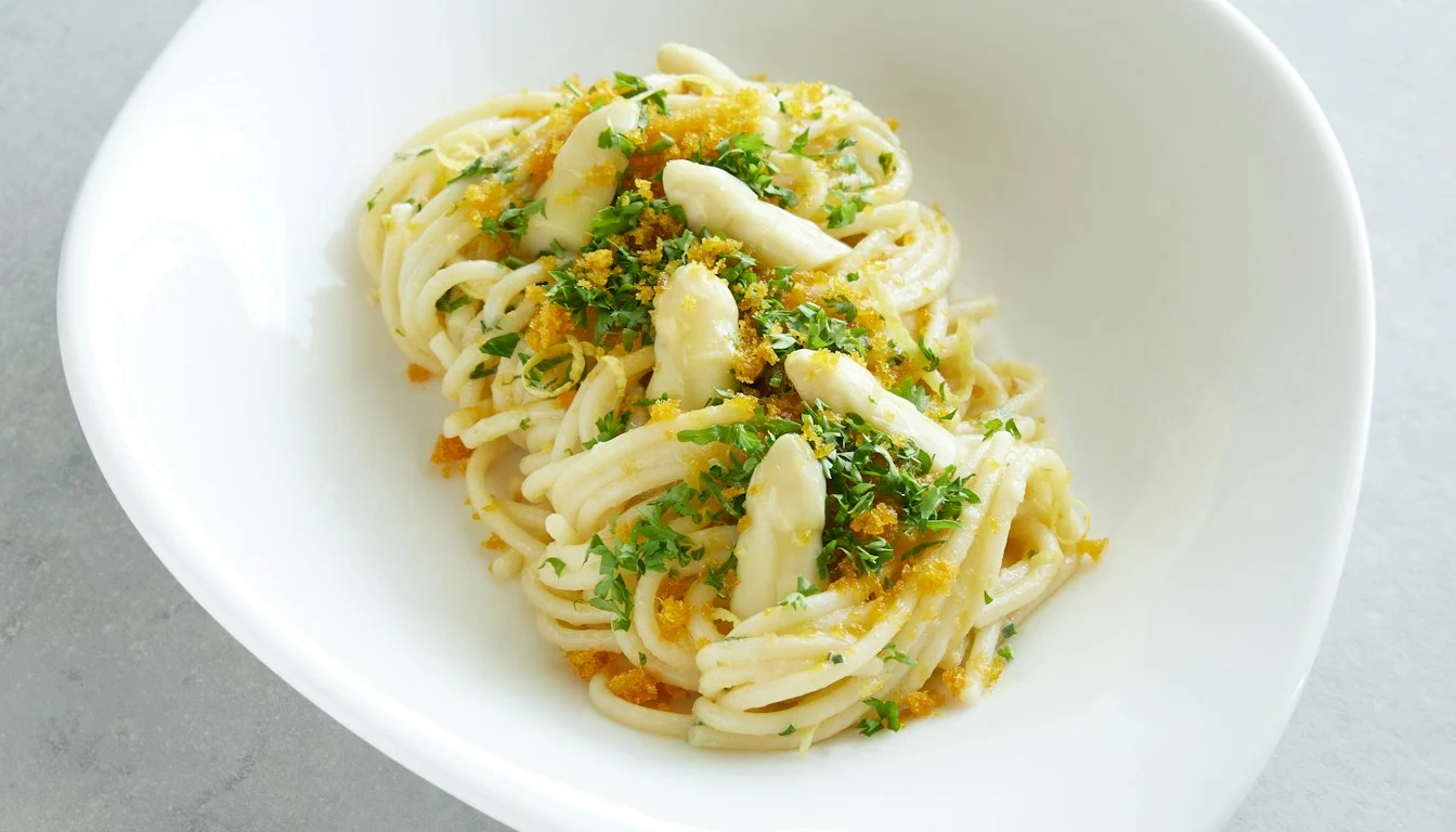 Pasta with green garnish in a white bowl on a gray surface